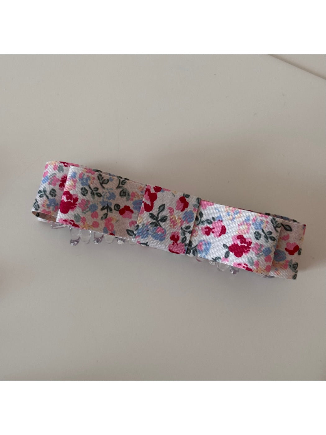 Beau hair clip placed on wooden surface highlighting floral pattern