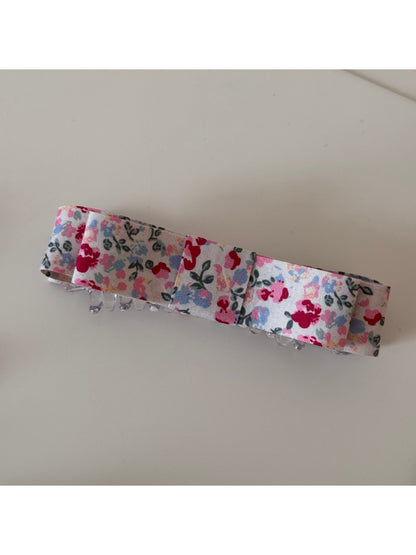 Beau hair clip placed on wooden surface highlighting floral pattern