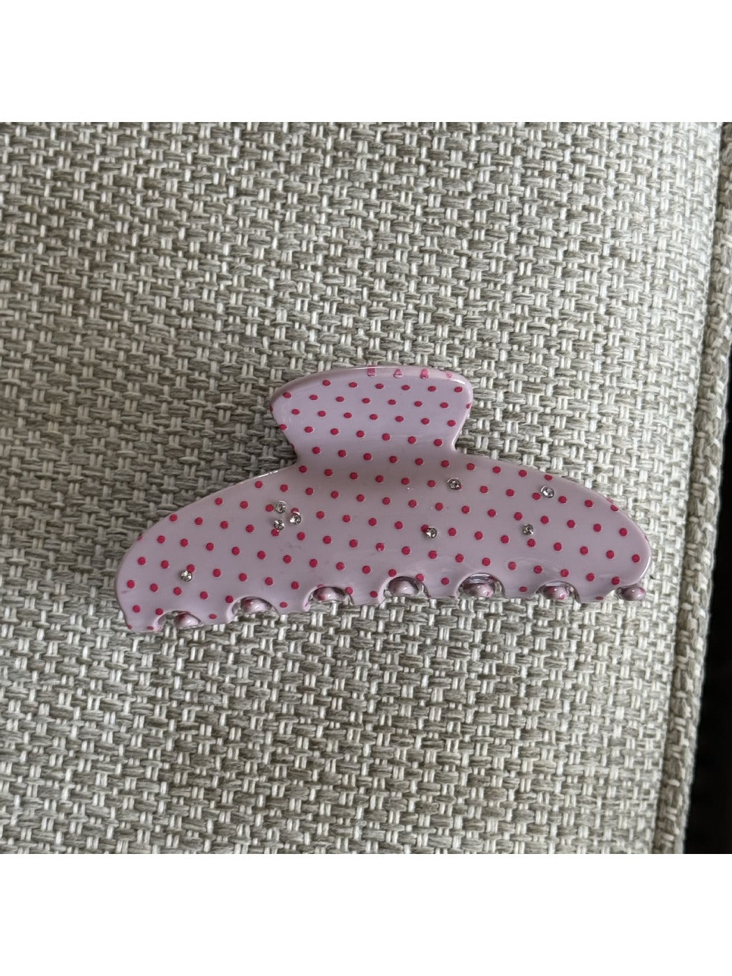Beau pink polka dot claw clip photographed with a pastel background for styling