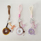 Pink donut keychain hanging from a set of keys on a wooden surface