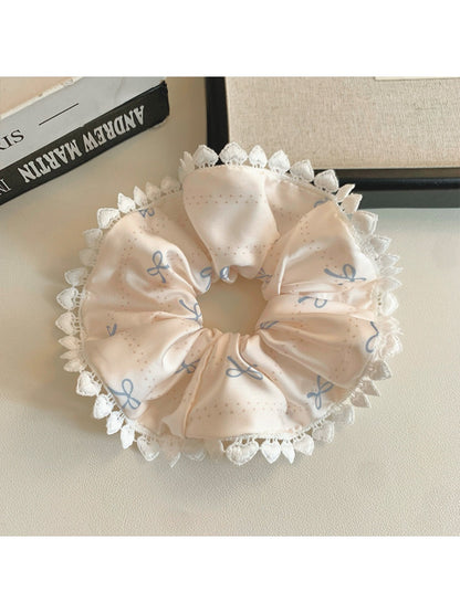 Gifty satin scrunchie with pink bows shown stretched on a white background