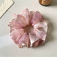 Side view of pink ruffled scrunchie highlighting fabric texture and gathers