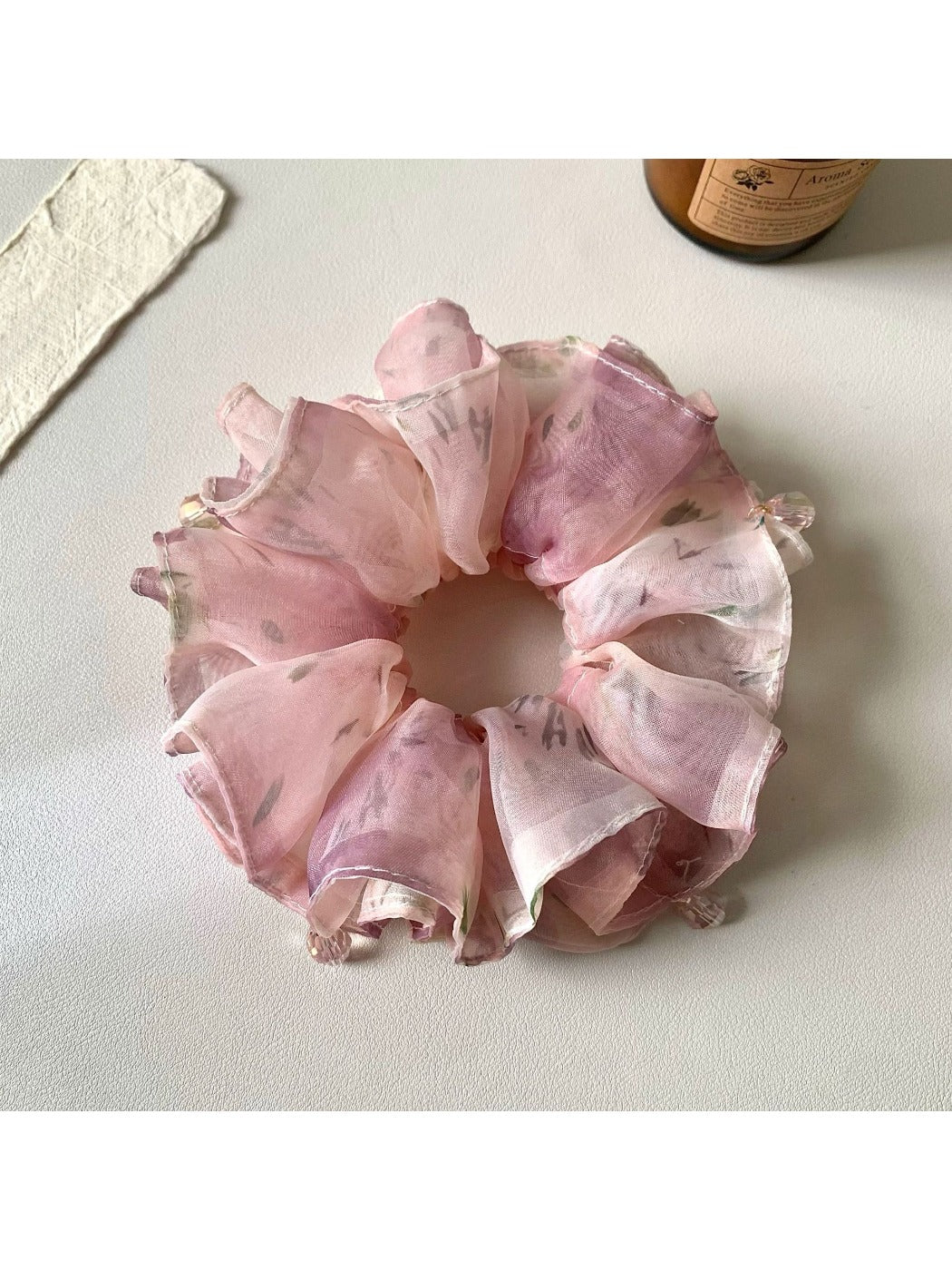 Side view of pink ruffled scrunchie highlighting fabric texture and gathers