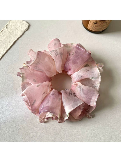 Side view of pink ruffled scrunchie highlighting fabric texture and gathers