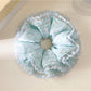 Lake blue floral scrunchie worn on a wrist as an accessory