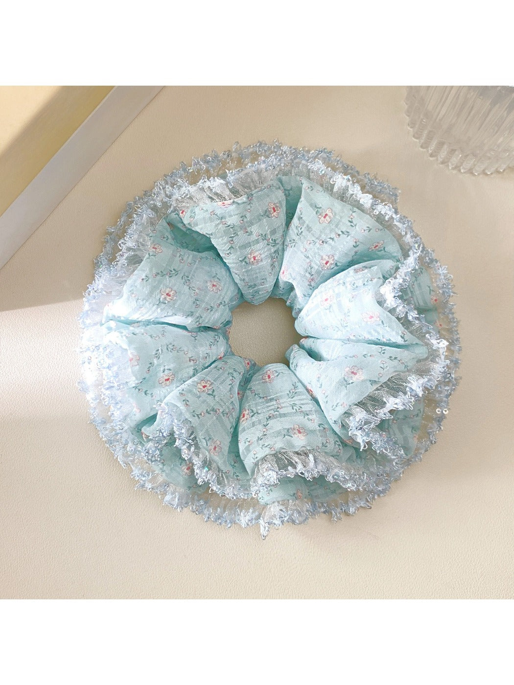 Lake blue floral scrunchie worn on a wrist as an accessory