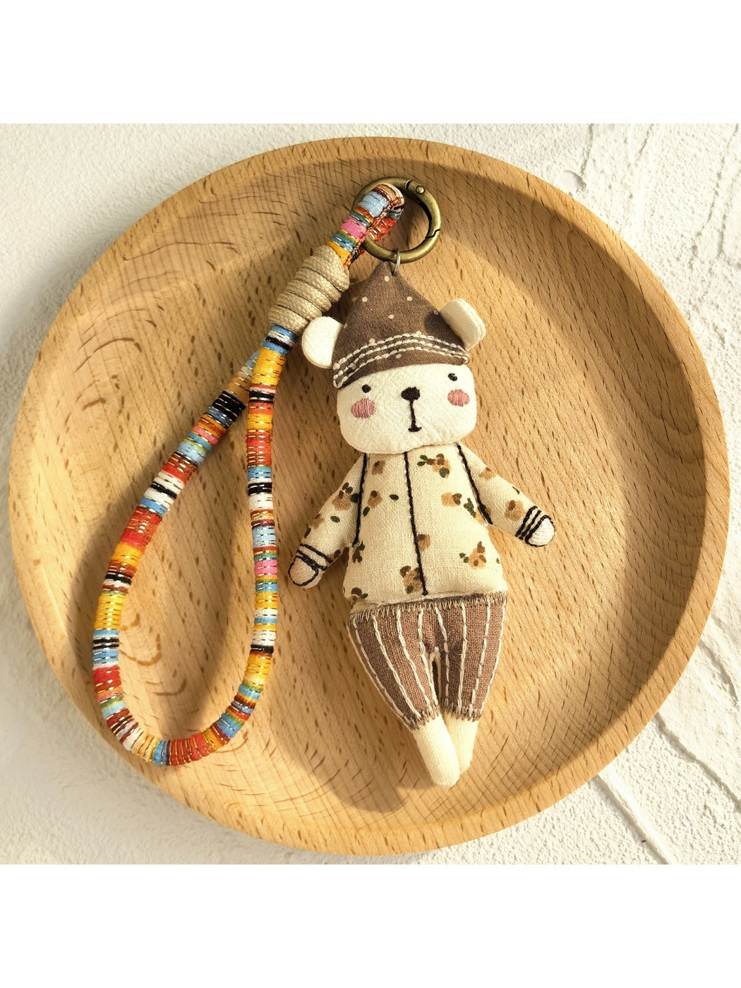 Keypus fabric doll keychain with smiling face and multicolor outfit on white background