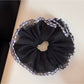 Gifty scrunchie held in hand demonstrating size and soft tulle material