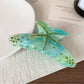 Colorful crescent hair claw clip displayed on a wooden surface with natural lighting
