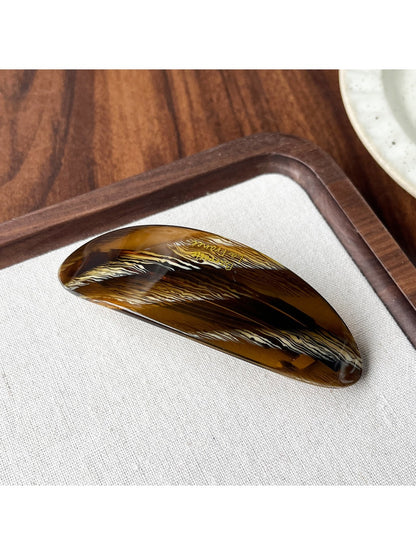 Beau oval ponytail clip shown from above with light reflecting on acetate surface