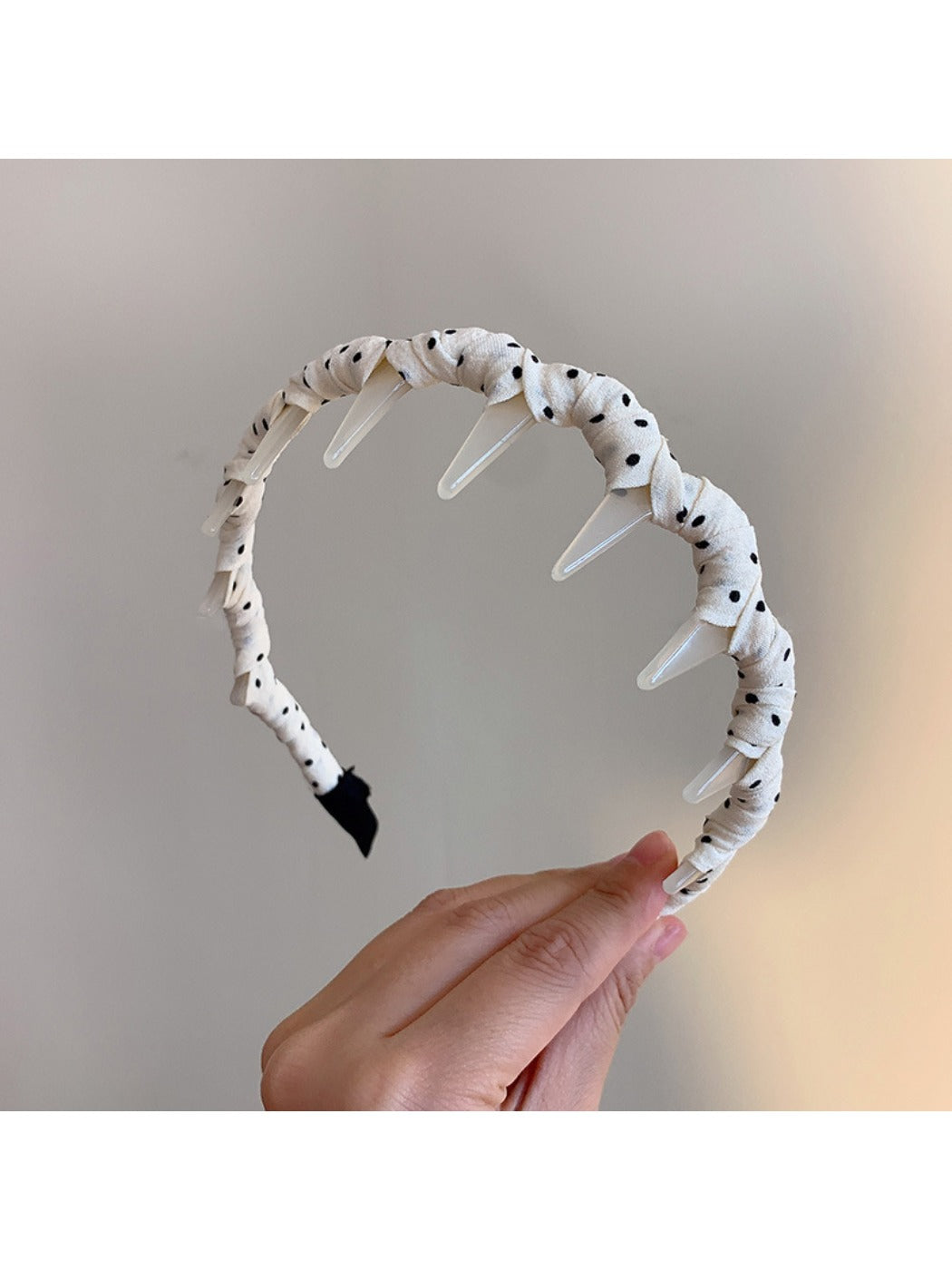 Close-up of black and white polka dot pattern on Gifty toothed comb headband