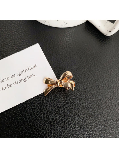 Beau classic bow hair clip resting on wooden surface with soft natural light