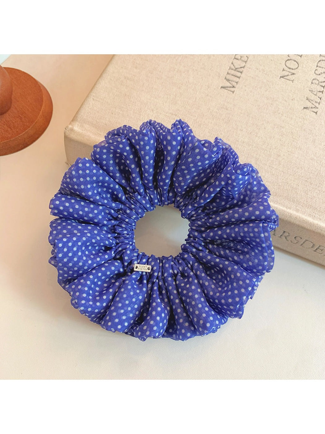 Blue scrunchie with white polka dots displayed flat showing full design