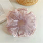 Pink scrunchie with soft ruffles displayed flat to show texture and design