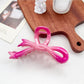 Beau heart shaped bow claw clip in pink to purple ombre gradient on a white marble surface