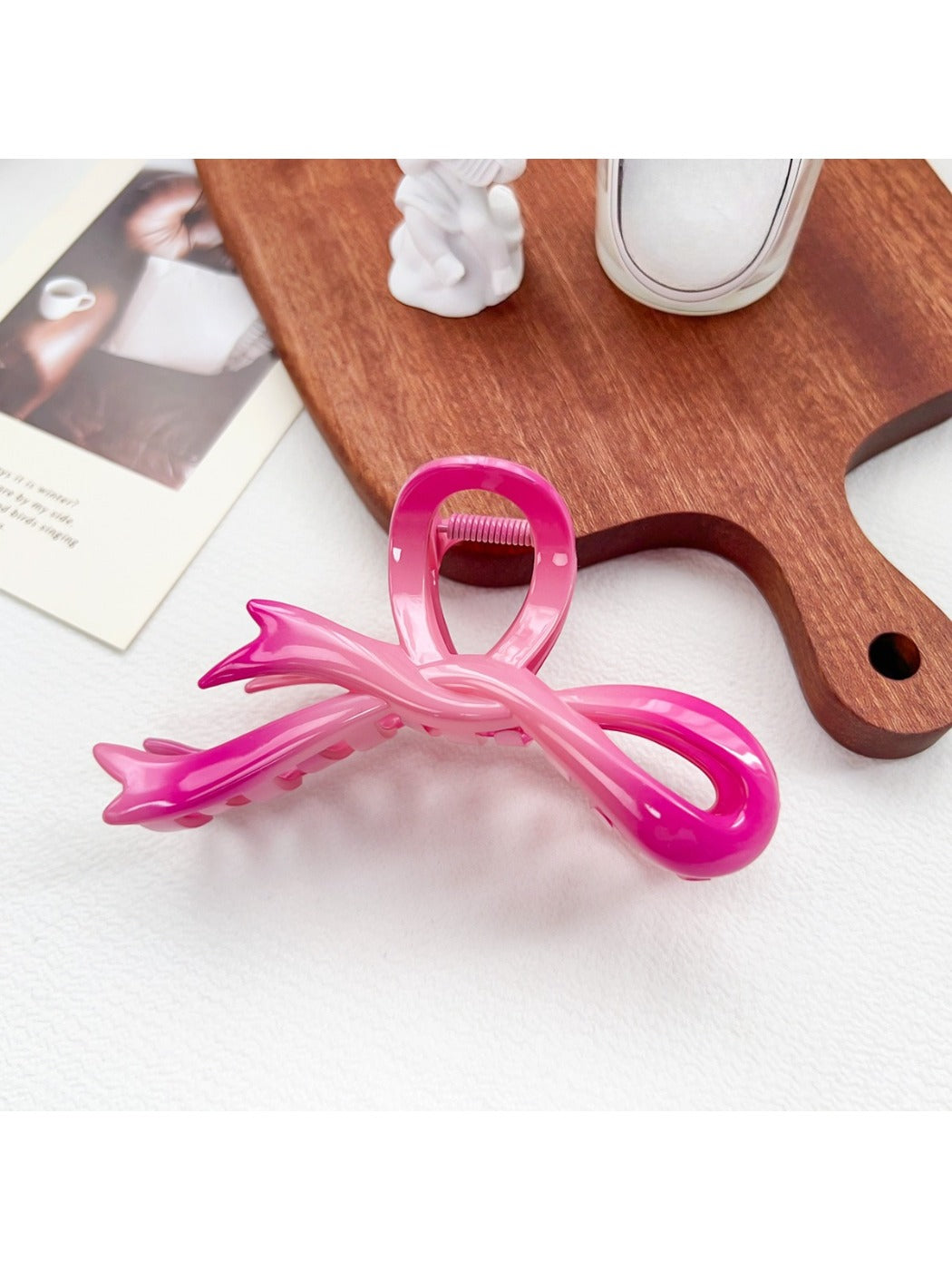 Beau heart shaped bow claw clip in pink to purple ombre gradient on a white marble surface