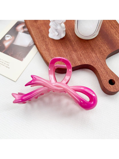 Beau heart shaped bow claw clip in pink to purple ombre gradient on a white marble surface