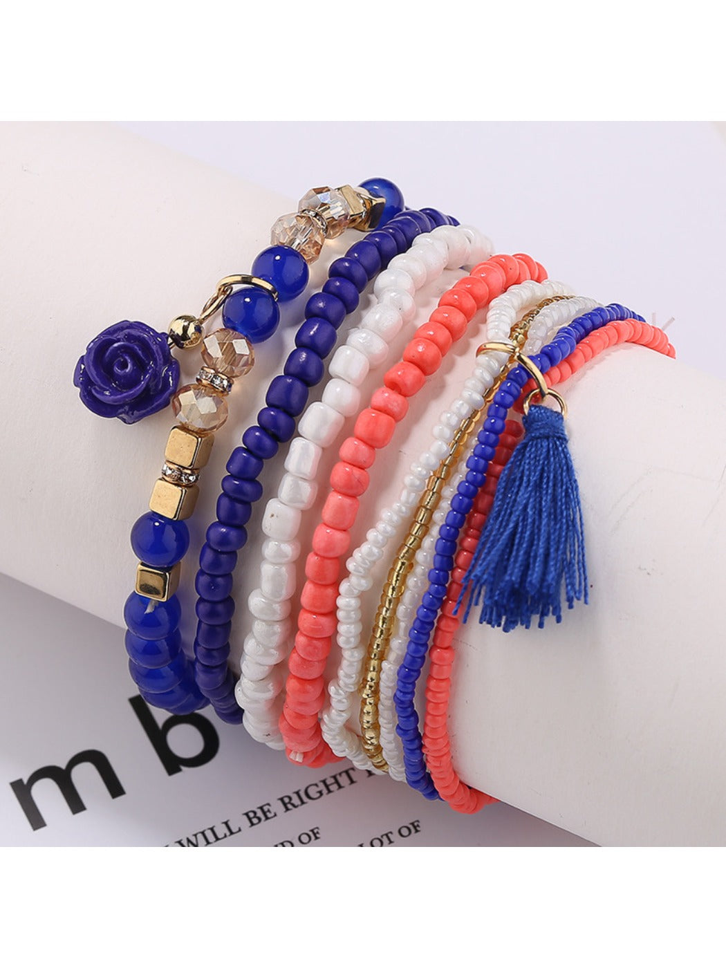 Lovra bracelet with pink beads and flower pendant displayed on a wooden surface