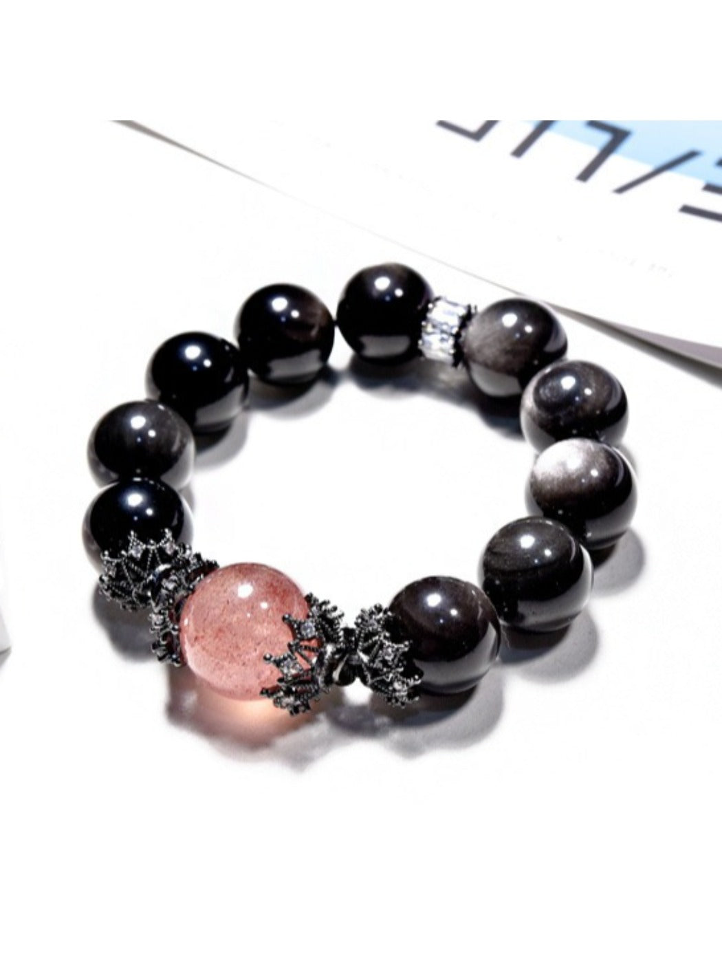 Lovra minimalist black crystal beaded bracelet coiled on a dark textured surface