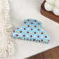 Blue hair claw clip with white polka dots shown from top angle