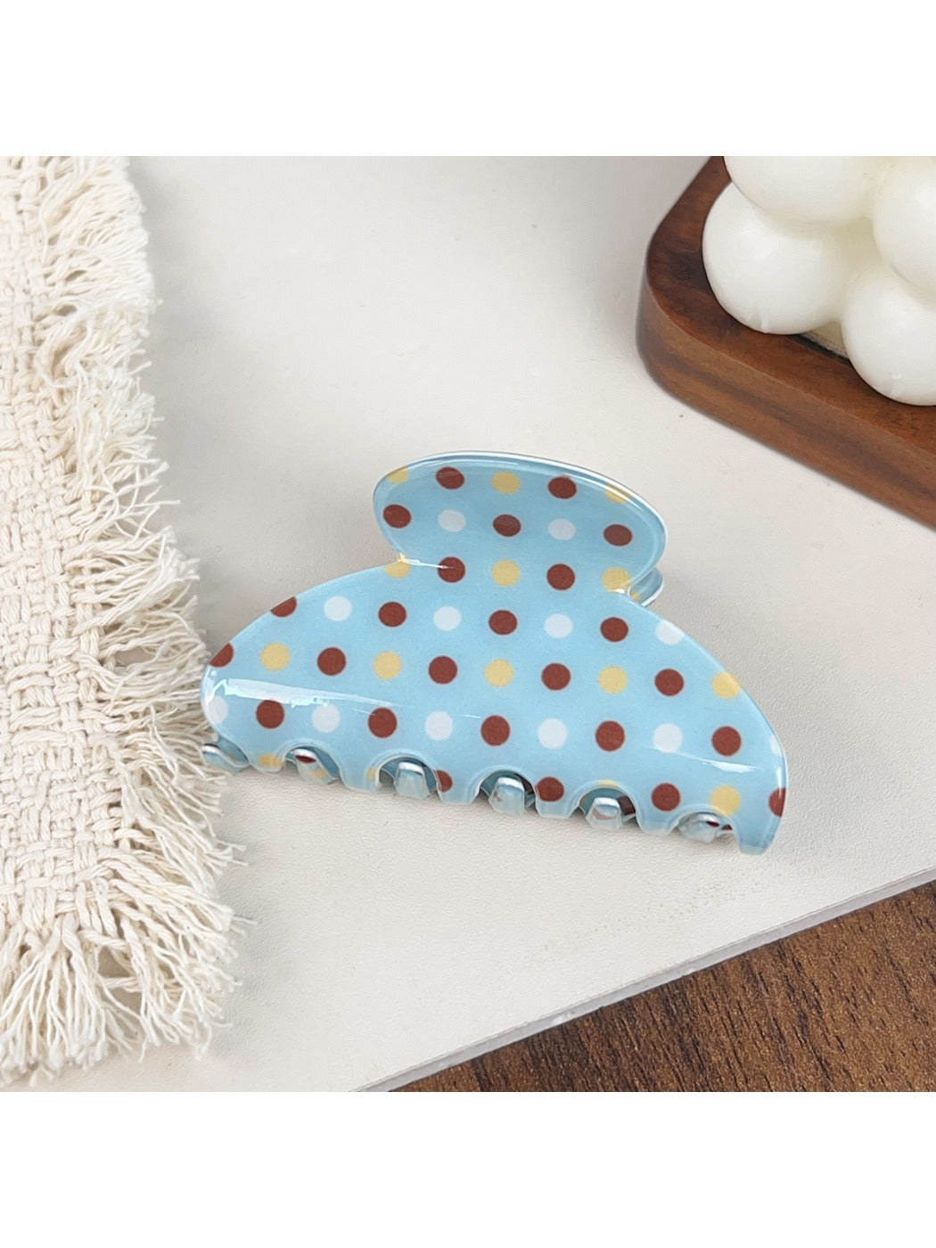 Blue hair claw clip with white polka dots shown from top angle