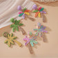 Earedge raffia palm tree earrings displayed on a wooden surface