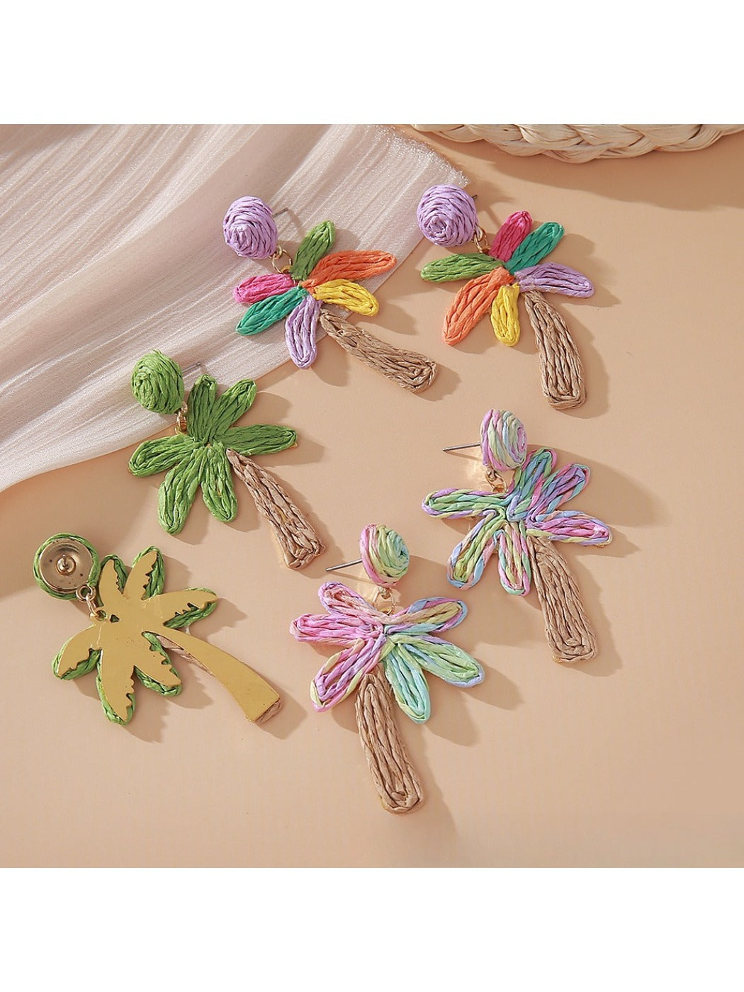 Earedge raffia palm tree earrings displayed on a wooden surface