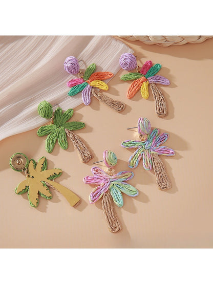 Earedge raffia palm tree earrings displayed on a wooden surface