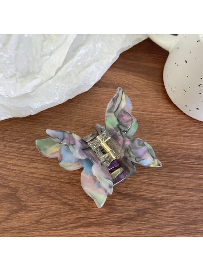 Butterfly shaped claw clip in pastel pink held in hand