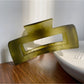 Beau hair claw clip resting on a fabric surface with soft shadows