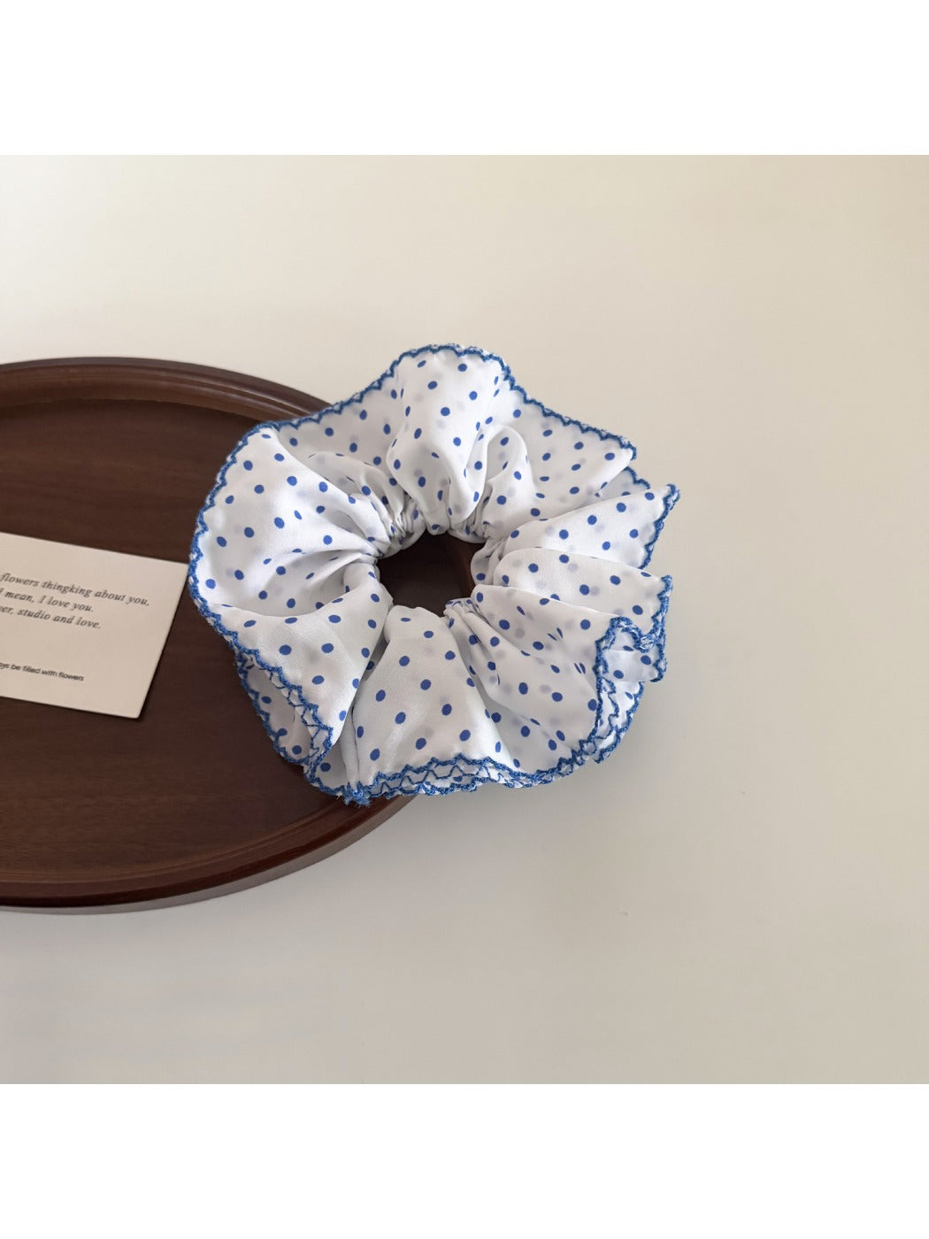 Blue polka dot scrunchie styled with casual outfit on table