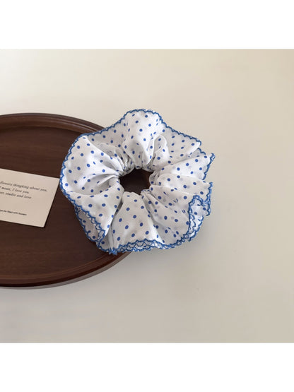 Blue polka dot scrunchie styled with casual outfit on table