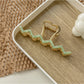 Beau wavy metal claw clip on a flat surface with light reflection