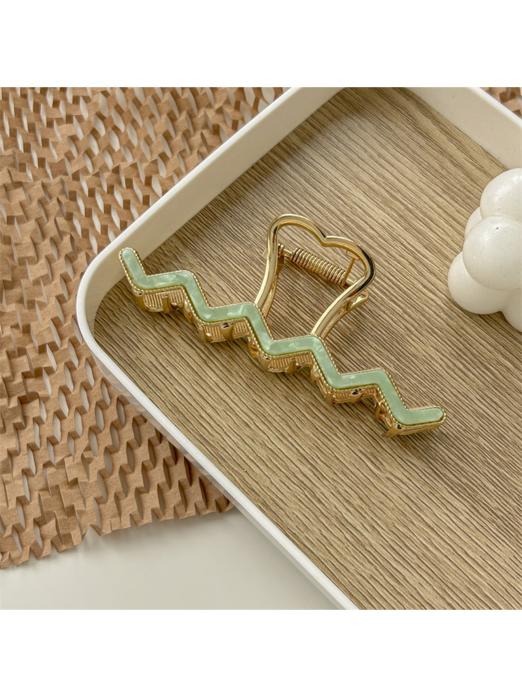 Beau wavy metal claw clip on a flat surface with light reflection