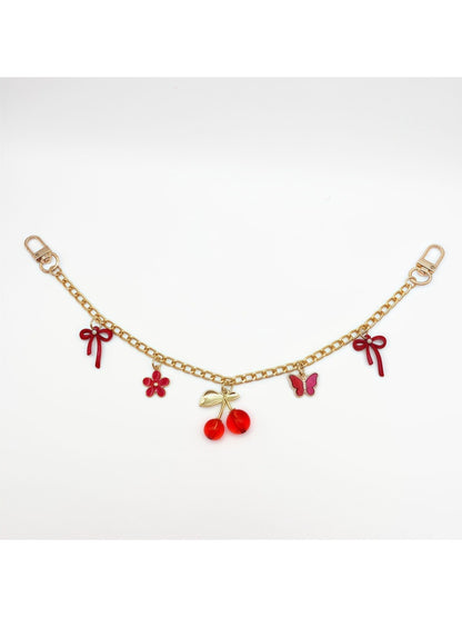 Minimalist cherry bag charm shown alongside a matching red wallet