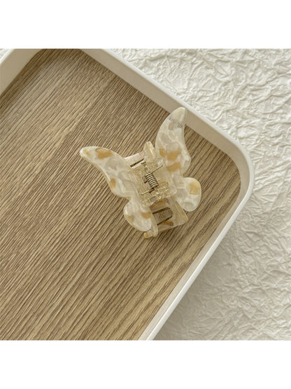 Beau light color butterfly claw clip placed on a wooden surface