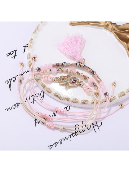 Detailed shot of tassel pendant hanging from Lovra alloy charm bracelet