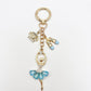 Ballerina charm keychain shown with other accessories on a wooden table