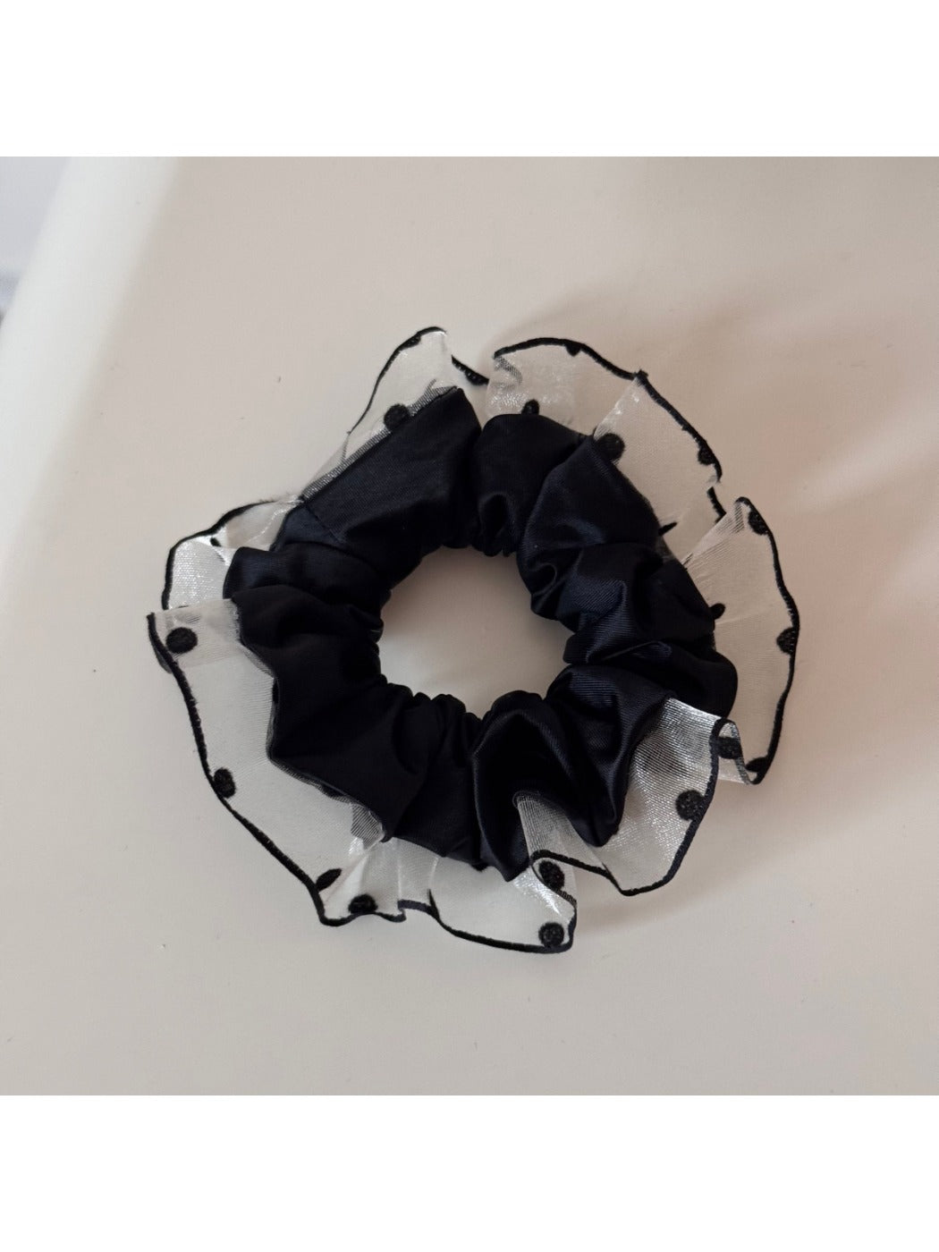 Black scrunchie with white polka dot trim shown from side angle
