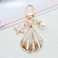 Gold conch keychain with keyring isolated on a light gray background