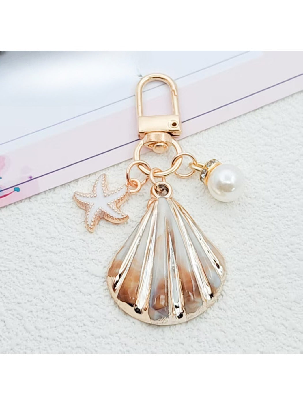 Gold conch keychain with keyring isolated on a light gray background