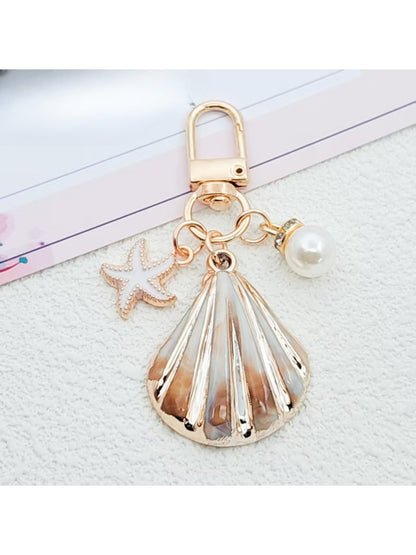 Gold conch keychain with keyring isolated on a light gray background
