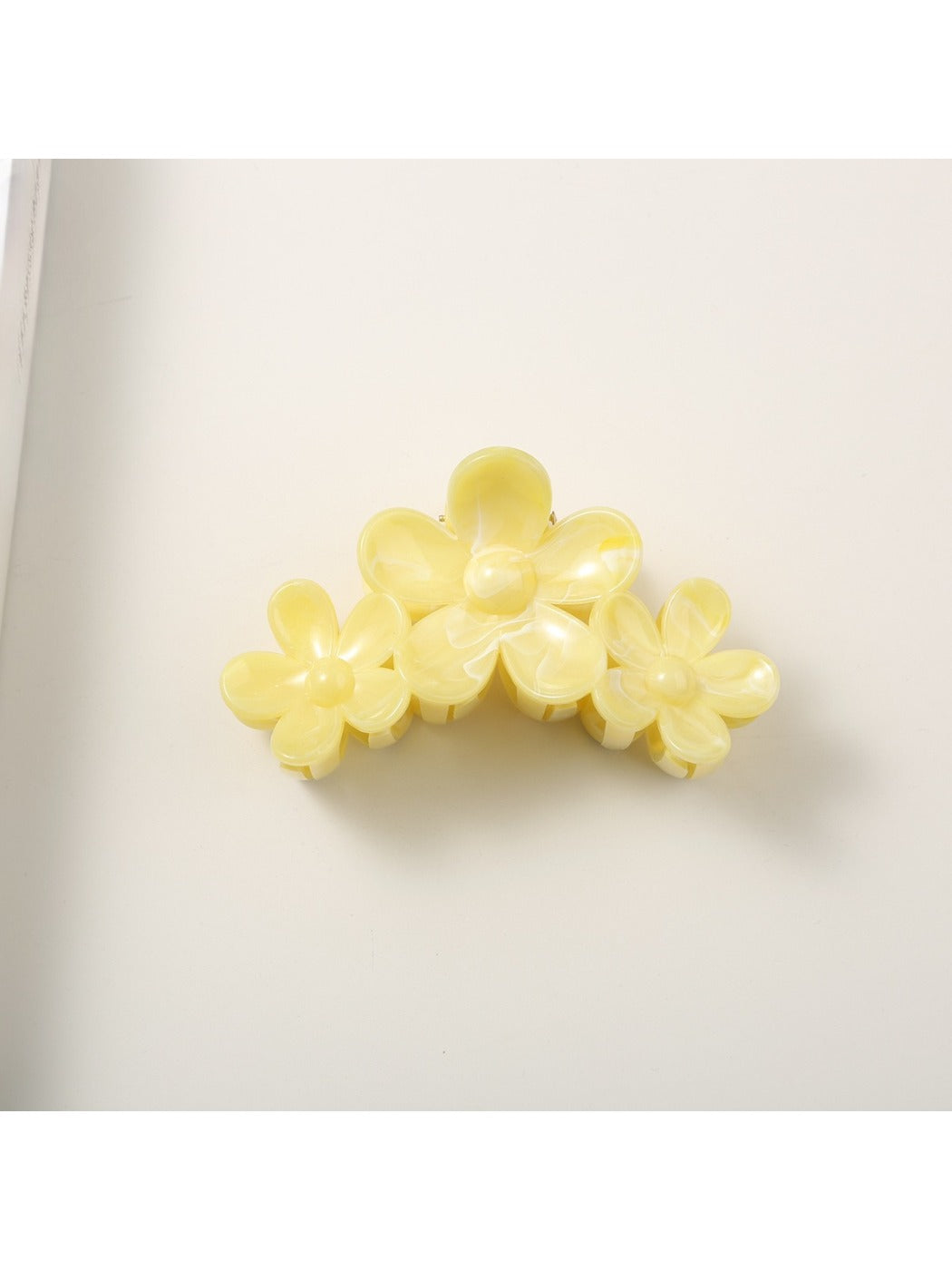 Top view of yellow flower hair clip with detailed petal design and pearl center