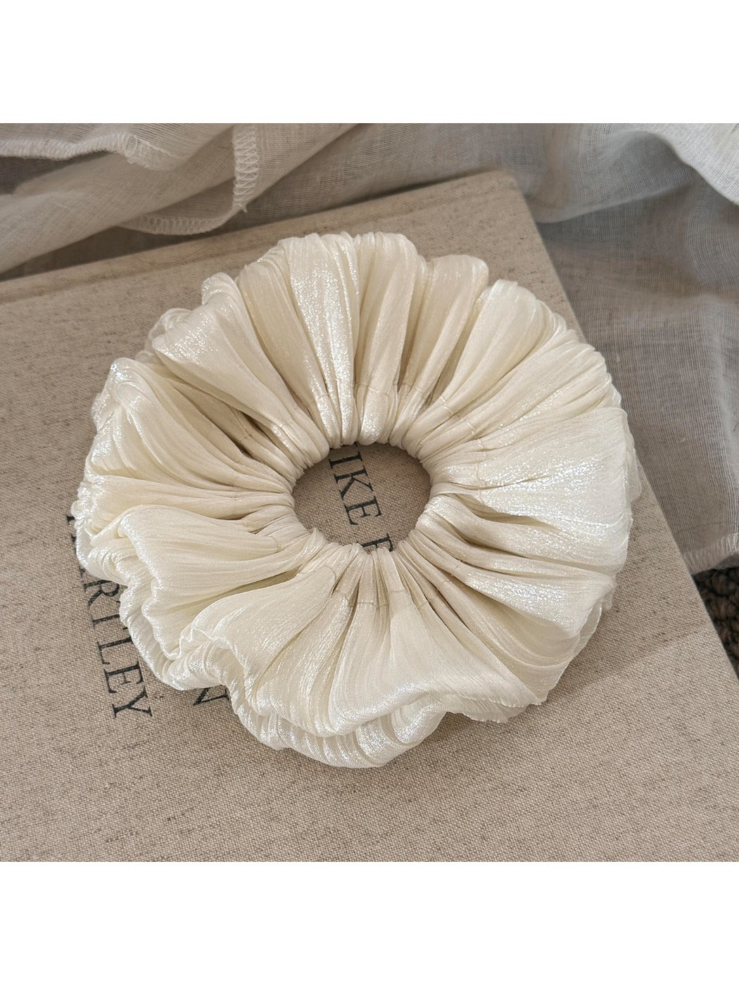 Close-up of the smooth satin material and ruched texture of the scrunchie