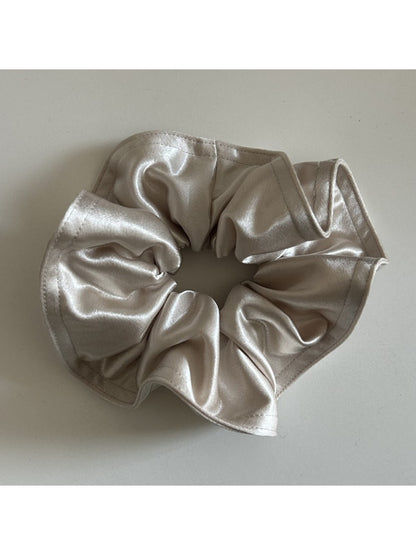 Gifty satin scrunchie held between fingers showing elasticity and fabric quality