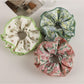 Close-up of Gifty trendy floral print scrunchie with pink and white flowers on fabric