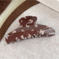 Top view of brown butterfly print claw clip showing symmetrical pattern