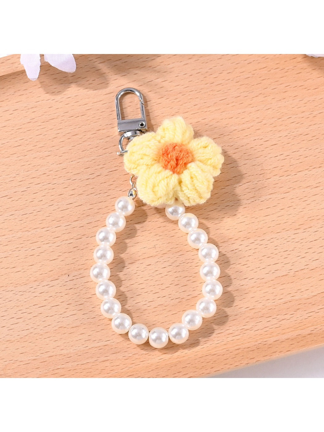 Yarn flower keychain with beads displayed alongside keys on a wooden table