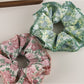 Gifty floral print scrunchie styled on a wrist with soft fabric and elastic band