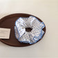 Blue scrunchie with white polka dots displayed on a wooden surface
